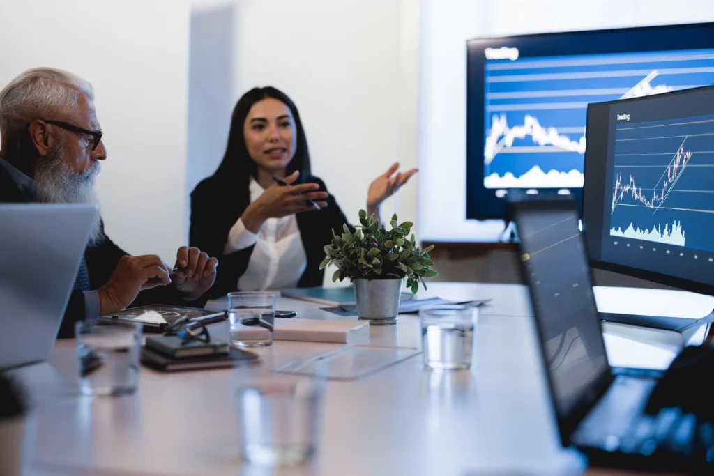 a lady and a man discussing trading strategies looking at trading charts