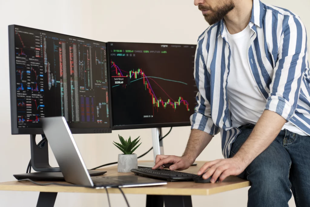 trader analysing trading charts on desktop while sitting on table
