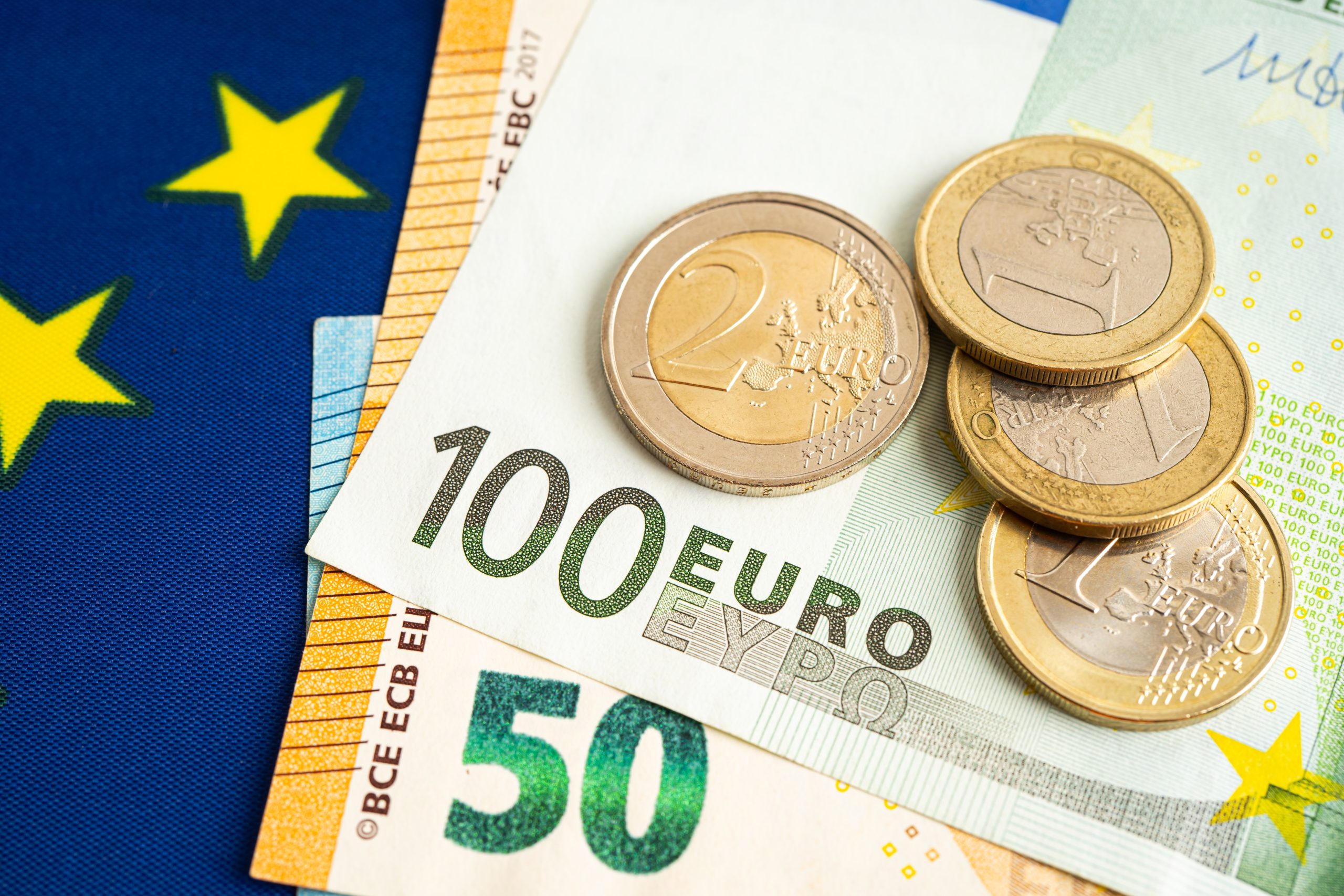 Euro banknotes and coins on a blue fabric surface.