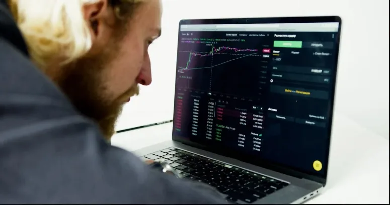 Trader studying a market chart and order panel on a laptop.