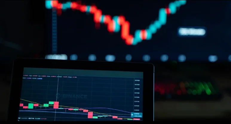 Red and green candlestick charts displayed on two screens.