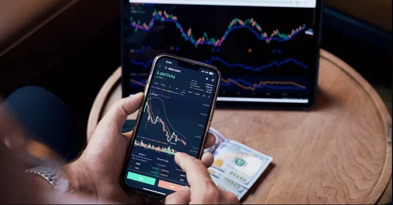 Trader viewing price charts on a smartphone and tablet beside dollar banknotes.